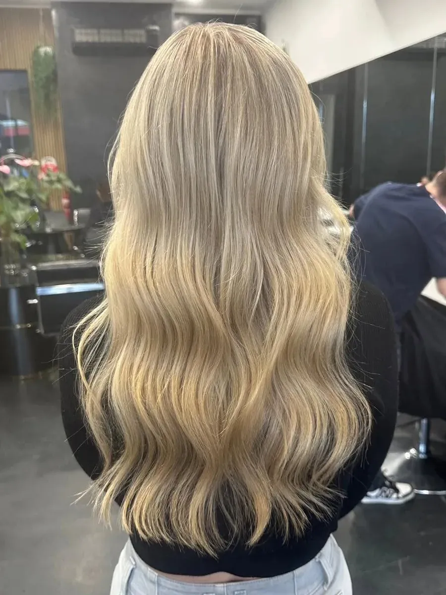 Long blonde hair with a natural root and waved ends, Rokk Ebony Malvern.
