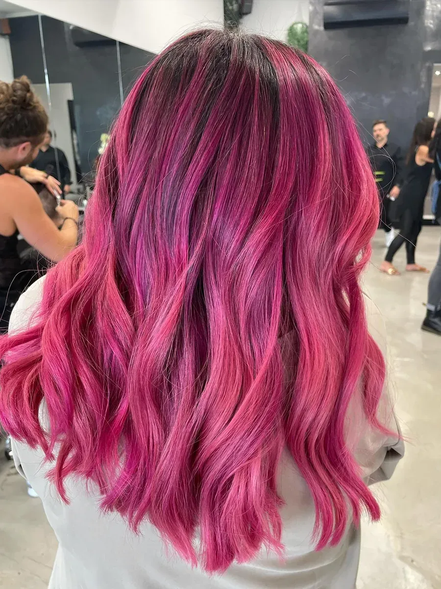 Mid-length hair in a vivid magenta over a dark root, Rokk Ebony Malvern.
